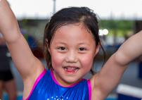 Young girl smiling and lifting arms in Skylark Sports class