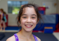 Young girl smiling at camera in gymnastics class