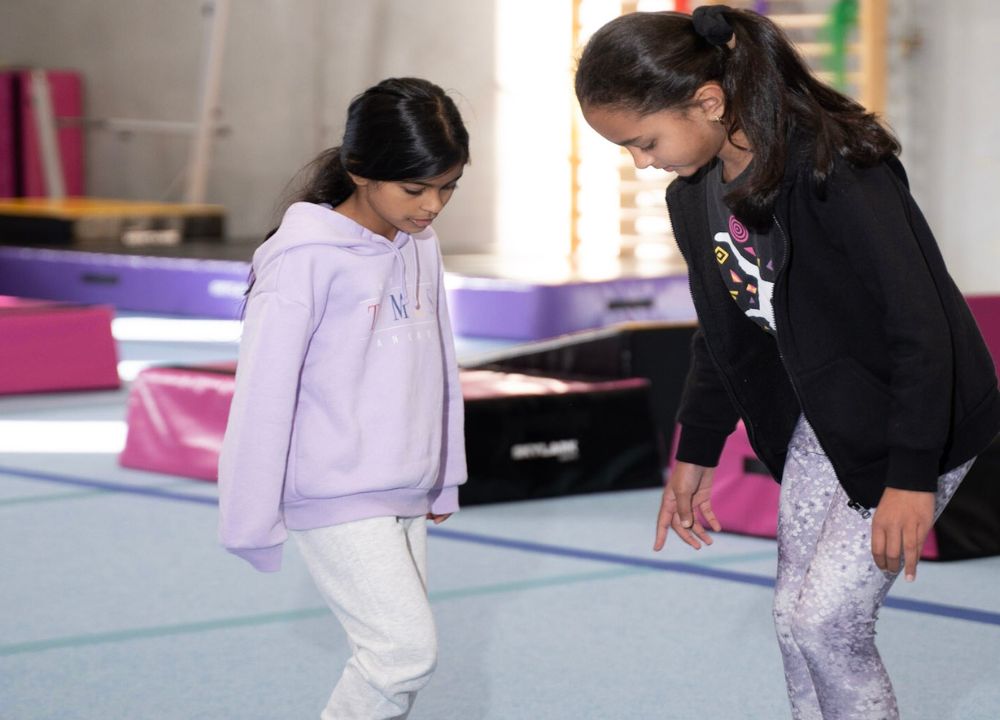 Two young girls practicing balance on a gymnastic training
