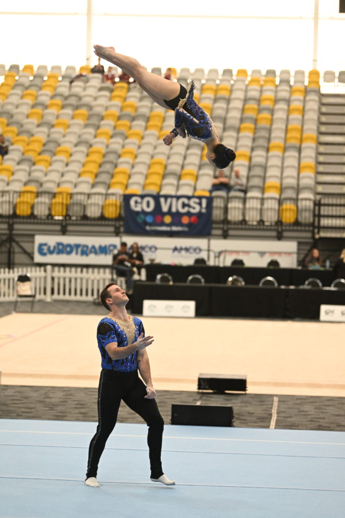 Mia performing layout sault above Alex's head during acrobatics competition