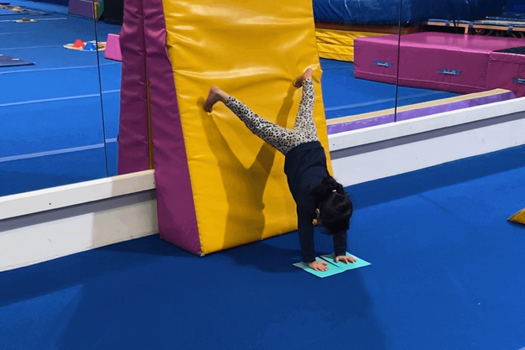 Kindergym gymnast doing star shape handstand