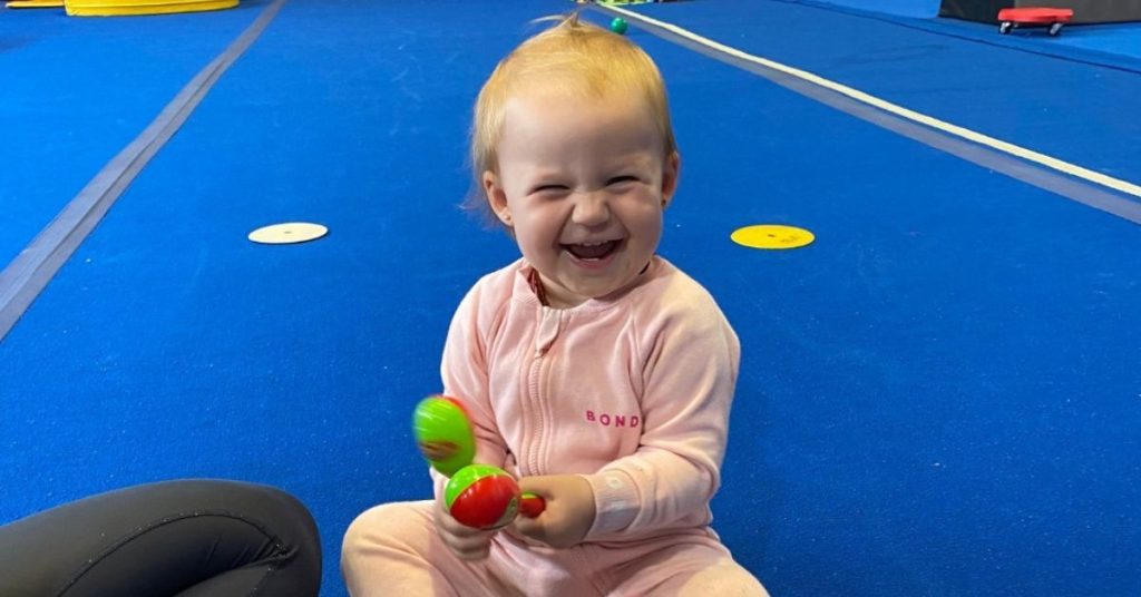 Happy toddler playing with toys in a gym class.